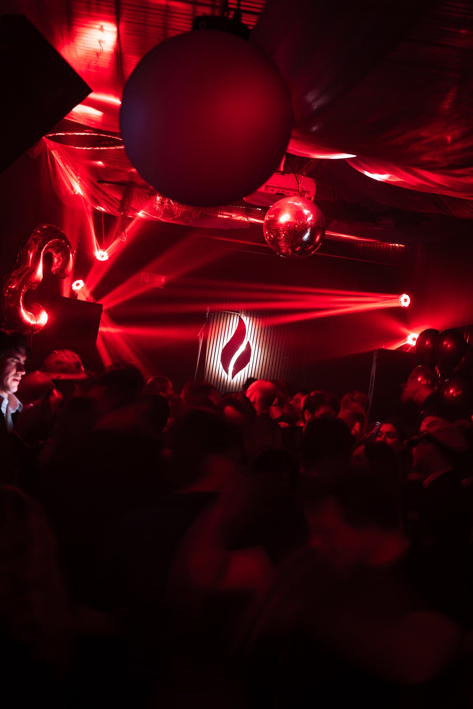 A packed dance floor in red light with Malja's flame on the wall